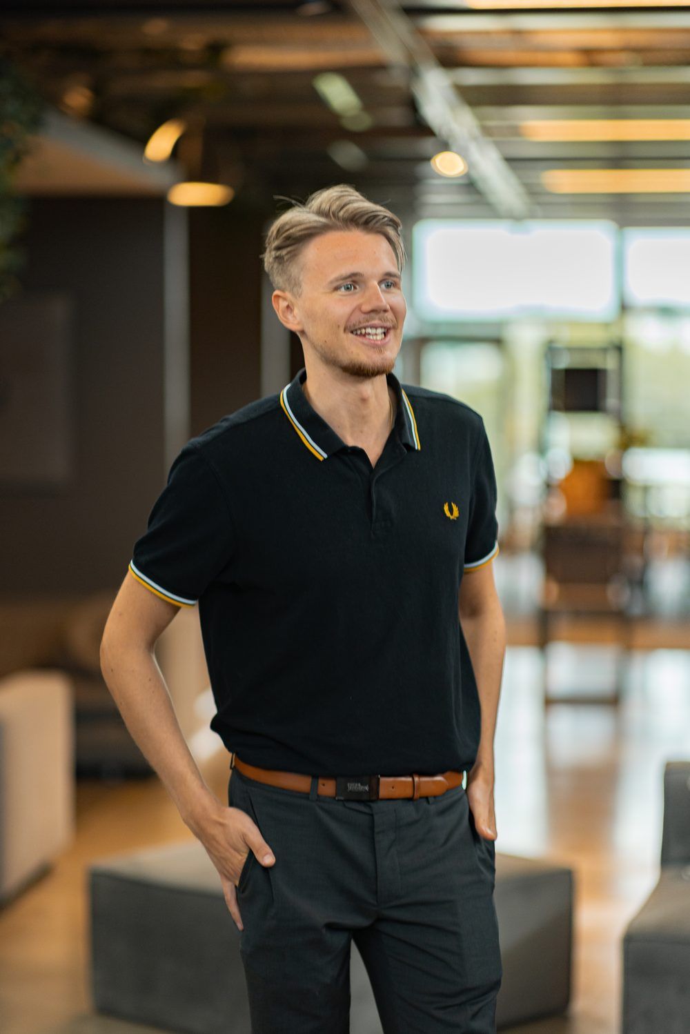 David Bacelj, smiling, in a black polo shirt in an office