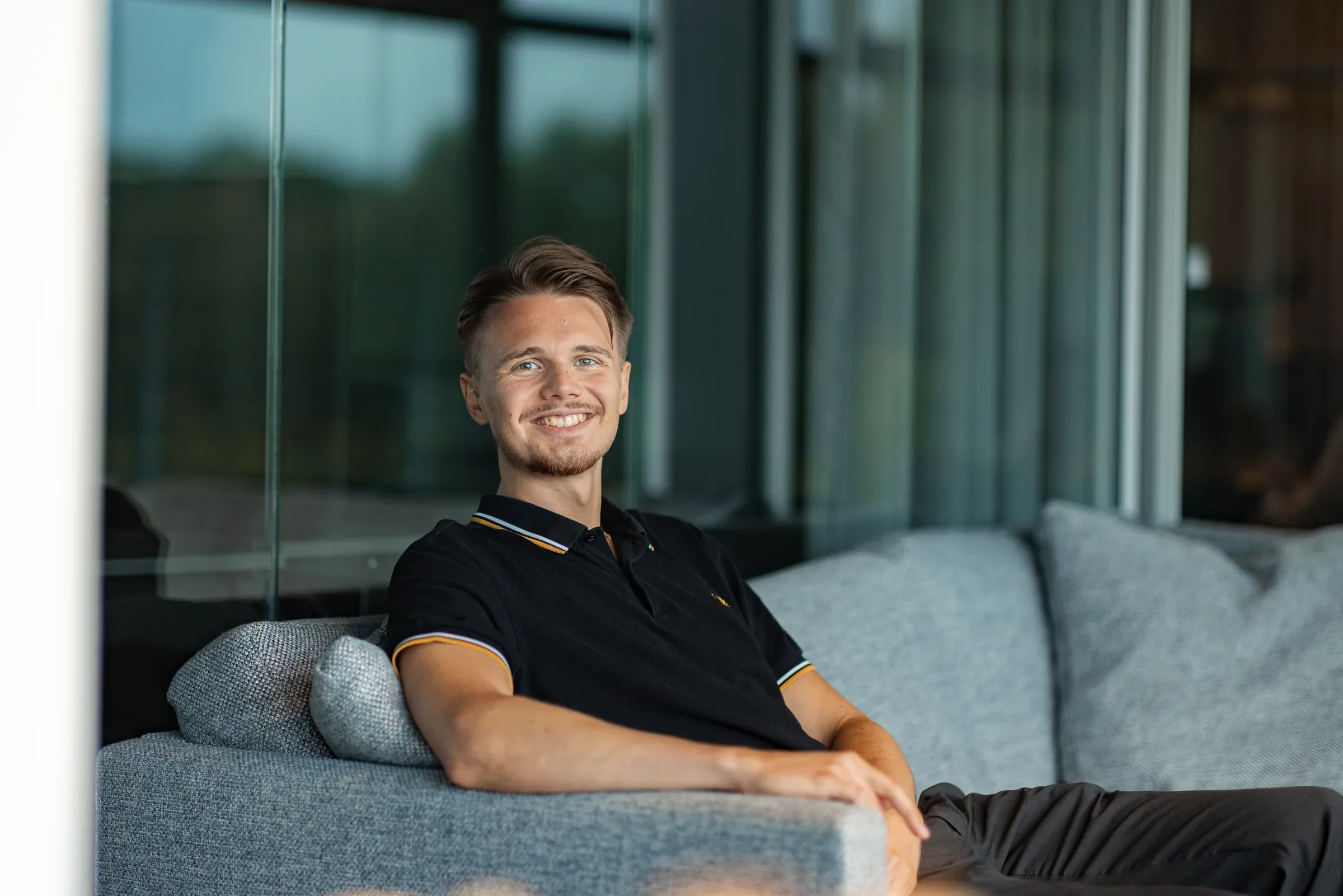 David Bacelj smiling on a sofa in the office
